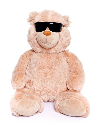 Teddy bear sitting over white background wearing black sunglassesの写真素材