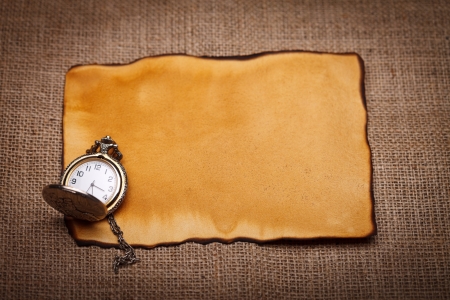 Old pocket watch on old paper with burlap background
の写真素材