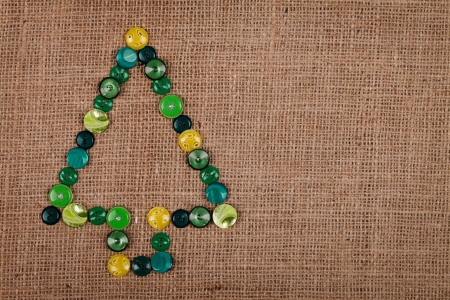 Contour of Christmas tree made of buttons, over burlap background
の写真素材