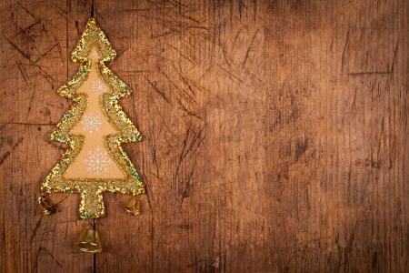 Christmas tree shape decoration with three golden bell on old scratched wooden background.
の写真素材