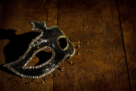 Black carnival mask with golden decoration on rustic wooden tableの写真素材