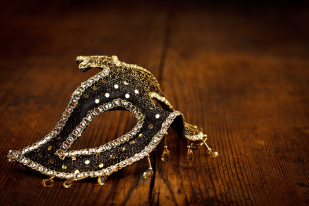 Black Venice mask with golden decoration on rustic wooden tableの写真素材