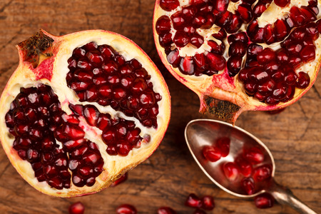 Upper view of grenadine fruits and seeds with silver teaspoon, rustic backgroundの写真素材