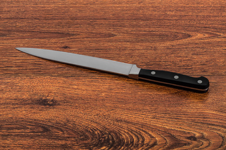 The big kitchen knife on a brown wooden tableの写真素材