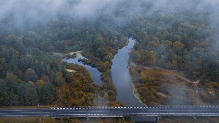 Aerial view of the forest and empty road under clouds during the autumn. River Sluch in Belarus.の写真素材