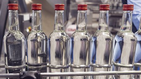 The bottles on the conveyor belt at the plant for bottling of alcoholic beverages, Russian vodkaの写真素材