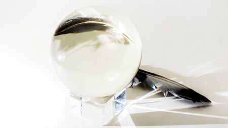 Religious round glass balls placed on a crystal platform with bird feather isolated on white background. Magic ball.の写真素材
