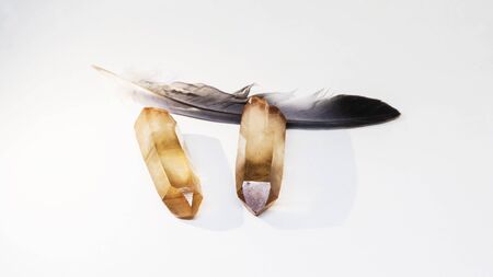 Pair smokey Quartz Polished Crystals Point and bird feather lying down on white background. Isolated...