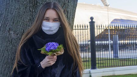 Portrait of the medical masked woman with flowers. Protective coronavirus concept.の写真素材