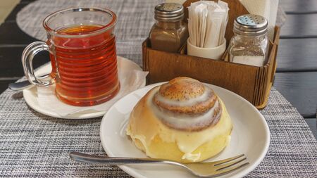 Sweet round bun and cup of tea on a beautiful napkin background. Bakery concept.の写真素材