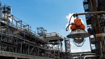 Industrial explosion proof lantern on the background of the refinery plant and classic blue sky.