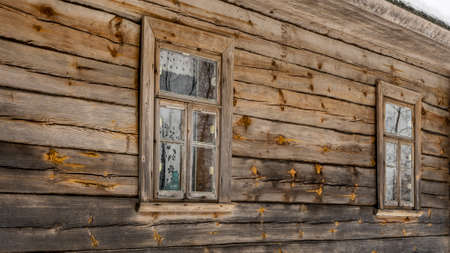 Boarded up windows on the old wooden wall of the house. Carving adorns the old window.の写真素材