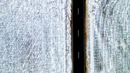 Top view from the air on the winter road in the field on which cars are going.の写真素材