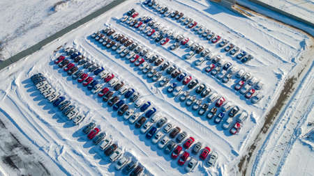 View from above at a large warehouse of new cars. Aerial view new cars lined up in the car warehouse for sale. Wintertime.の写真素材