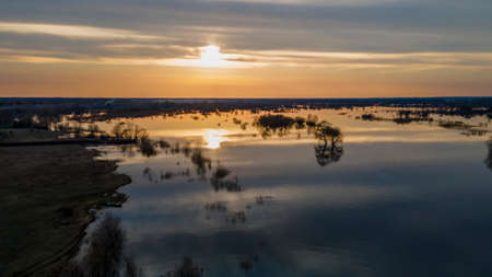 Aerial view of the setting sun beautifully illuminates cumulus clouds slowly floating over a...