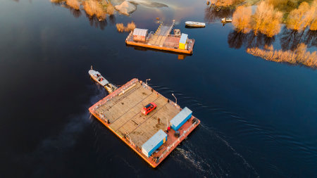 Aerial view of small wooden ferry crossing the river with orange car on it. Traditional ferry boat on water.の写真素材