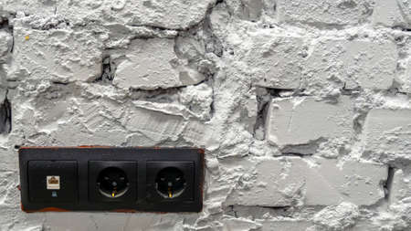 White brick wall with black electrical outlets.