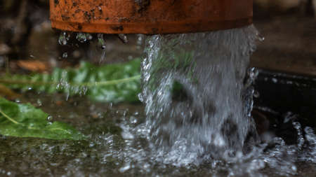 Heavy rain. Rainwater flows from the roof through the drainpipe. Rainy season.の写真素材