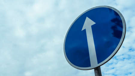 Traffic road sign straight ahead on cloudy blue sky background.