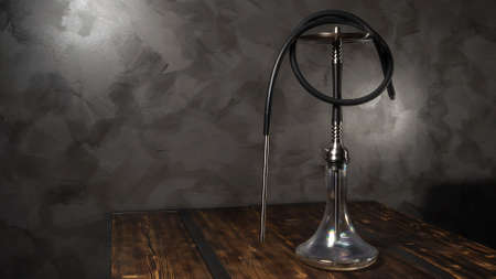Modern hookah with glass bowl on wooden table. Gray wall background.