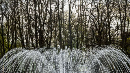Water from the fountain. Top of high water stream of fountain behind cloudy sky. Fountain in river against dramatic sky.の写真素材