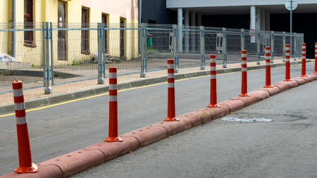 Row of red and white traffic barrier pole on road. A barrier made of plastic columns with reflective pigment on an asphalt road. Danger concept.の写真素材