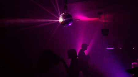 Silhouette image of people dance in disco night club to music from DJ on stage.の写真素材