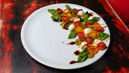Caprese salad. Healthy meal with cherry tomatoes, mozzarella balls, spices, fresh rocket and basil. Home made, tasty food. Symbolic image. Concept for a tasty and healthy vegetarian meal. Close-up.の写真素材