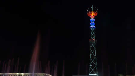 Glowing TV tower at night. Festive illuminated broadcast tower. Space for text.