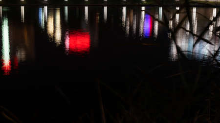 City lights Reflextion. Multi-colored neon lights on a dark city street, reflection of neon light in...