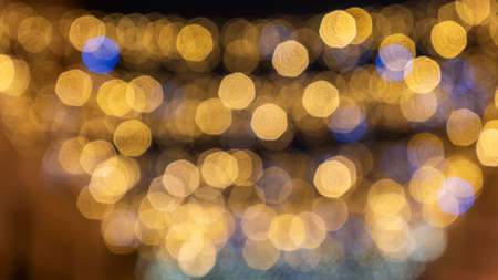 Defocused Christmas lights garland border over black background. Flat lay, copy space.