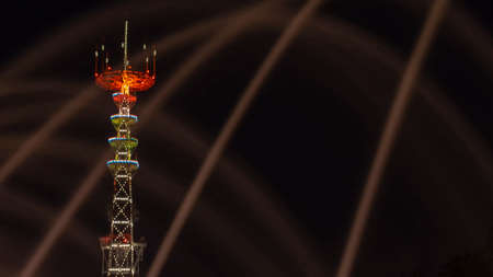 TV Tower in festival illumination. On foreground fountain with long exposure water drop. Minsk Day celebration with bright firework in river.の写真素材