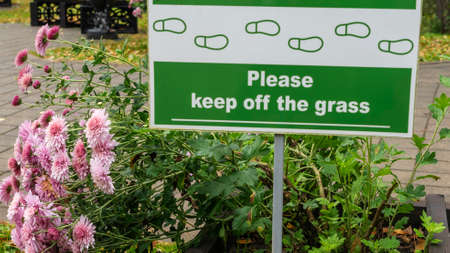 Sign Do Not Walk On The Grass with pink flowers. No Sign Of Trampling The Lawn. Nature concept.の写真素材