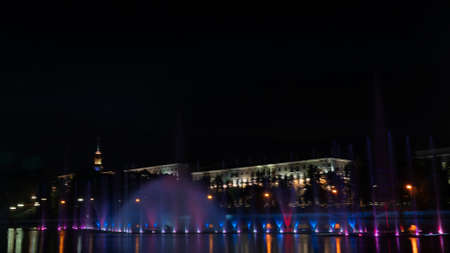 Multicolored musical fountain on a river at night. The fountain in the night from illumination. Space for text. Festive concept.の写真素材