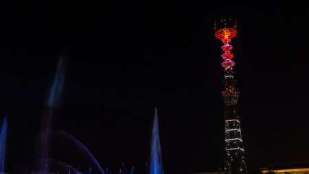 TV Tower in festival illumination. On foreground fountain with long exposure water drop. Minsk Day celebration with bright firework in river.の写真素材