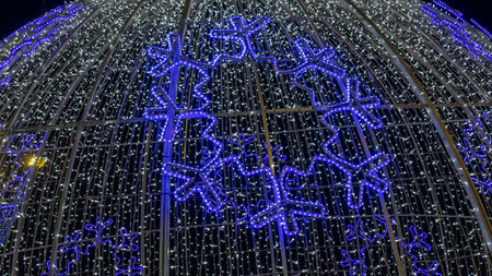 Blue illuminated ball with garland and snowflake. Christmass garland coiled on a large steel spherical frame. LED light background.の写真素材