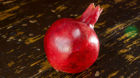 Fresh whole juicy pomegranate on wooden table background. Close-up view of ripe red pomegranate. Healthy food concept.の写真素材