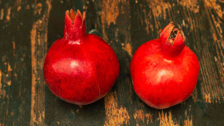 On the table lay two red pomegranate. Two ripe garnet on the wooden table. Haealthy food. Still life...
