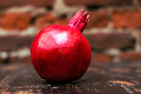 Fresh whole juicy pomegranate on wooden table background. Close-up view of ripe red pomegranate. Healthy food concept.の写真素材