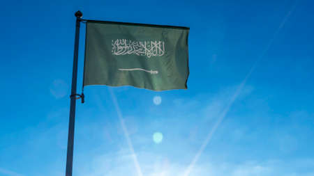 Flag of Saudi Arabia against the blue sky with sun rays. Diplomacy concept. International relations....