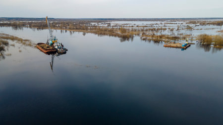 Floating crane on the river. Dredging crane working near shore. Conservation river flow. Nature, river, sky, clouds. Cleaning the bottom of the river.の写真素材