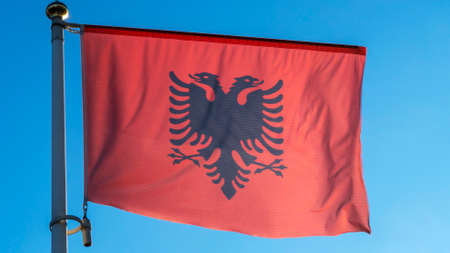 Albania national flag cloth fabric waving on the sky with beautiful sun light. Diplomacy concept. International relations. Space for text.の写真素材