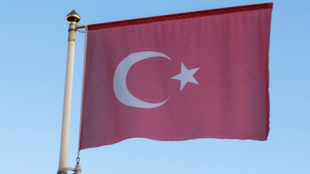 National flag of Turkey on a flagpole in front of blue sky with sun rays and lens flare. Diplomacy concept. International relations. Space for text.の写真素材