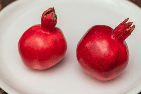 Two fruit juicy Spanish pomegranate on porcelain plate. Healthy life concepts.の写真素材