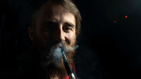 Groomed bearded man is relaxing on lounge while smoking hookah. Close-Up view Of Man Smoking Hookah. Relax and addiction concepts.の写真素材