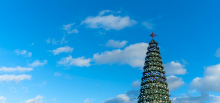 Stars on an artificial Christmas tree on a street against a classic blue sky with clouds. Space for text. Xmas concepts. Festive street decoration.の写真素材