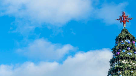 Stars on an artificial Christmas tree on a street against a classic blue sky with clouds. Space for text. Xmas concepts. Festive street decoration.の写真素材