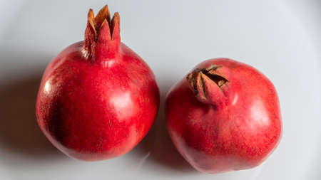 Two fruit juicy Spanish pomegranate on porcelain plate. Healthy life concepts.の写真素材