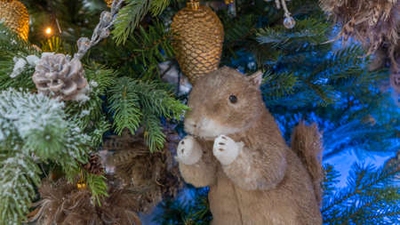 Toy squirrel or gopher sitting on a fluffy fir branches. Merry Christmas and Happy New Year Greeting Card Design. The concept of New Year and Christmas. Festive decoration.の写真素材