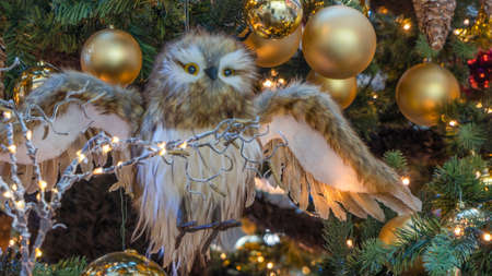 Toy owl flies in the fairy forest against the backdrop of the Christmas tree. The concept of the New Year. Xmas concepts. Festive decoration.の写真素材